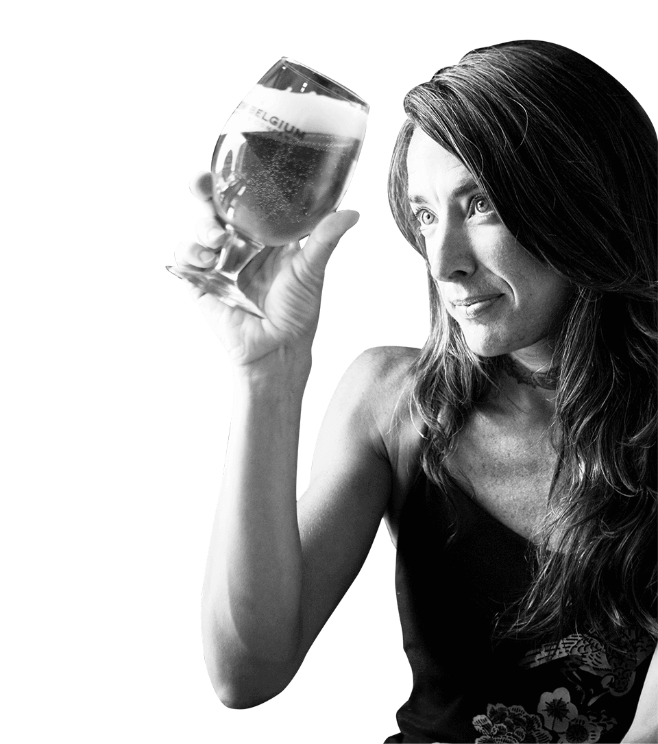 Wood Cellar director and blender, Lauren Limbach, intently examining a globe glass of beer.